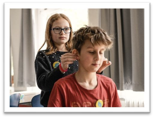 Ein Mädchen hält die Ohren eines Jungen aufrecht.